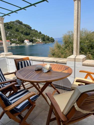 een houten tafel en stoelen op een patio met uitzicht op het water bij Beach house Evita in Prožura