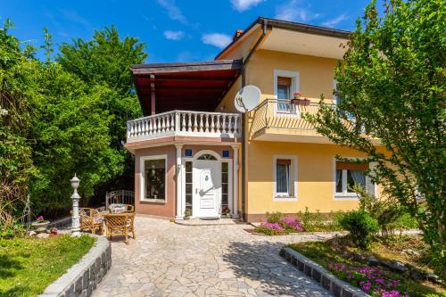 a yellow house with a balcony and a patio at AUTOMOTODROM GROBNIK - Apartments and Rooms Skejić in Čavle