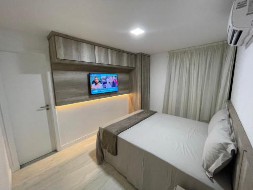 a bedroom with a bed and a tv on a window at Apartamento na Praia dos Anjos in Arraial do Cabo