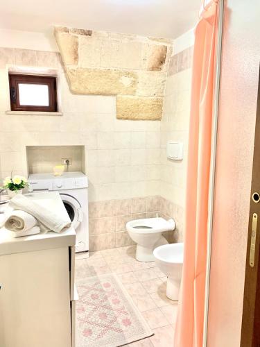a bathroom with a toilet and a washing machine at LA PICCOLA DIMORA in Carovigno