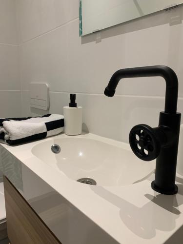 La salle de bains est pourvue d'un lavabo avec un robinet noir. dans l'établissement A 2 PAS DU VIEUX PORT Charmant T2, à Marseille