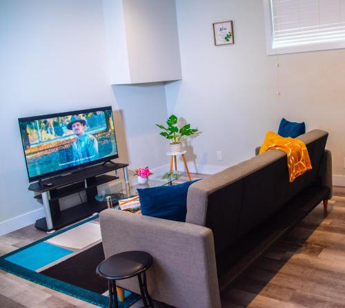a living room with a couch and a tv at AIR & ROAD TRAVELERS' PERFECT SPOT! + FULL KITCHEN in Regina