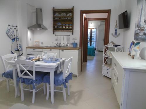 una cucina con tavolo e sedie bianchi in una stanza di L'Ancora suite a Orosei