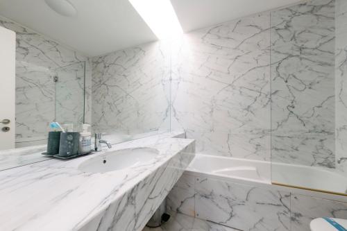 a white bathroom with a sink and a tub at Casa da Ria in Torreira