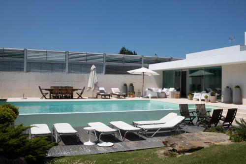 a swimming pool with lounge chairs and a table at Casa da Ria in Torreira