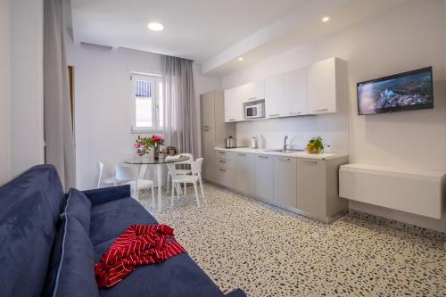 a living room with a blue couch and a kitchen at Neva Suites Massa Lubrense Sorrento Coast in Massa Lubrense