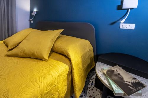 a bed with a yellow blanket and a blue wall at Neva Suites Massa Lubrense Sorrento Coast in Massa Lubrense