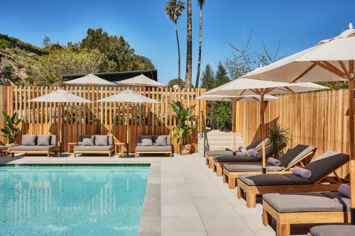 a pool with lounge chairs and umbrellas next to a fence at Hotel June Malibu in Malibu