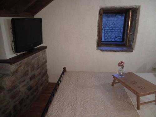 a living room with a flat screen tv and a table at Stone house Castellum in Kaštela