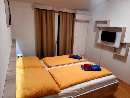 a bedroom with two beds with yellow sheets and a television at VILLA NIKOLINA in Medulin