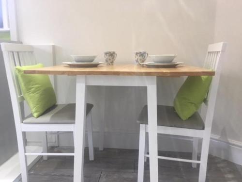 a wooden table with two chairs and two bowls on it at Townhouse @ Westminster Street Crewe in Crewe
