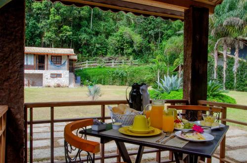 a table with plates of food on a porch at Recanto Meu Pedacinho de Chão in Visconde De Maua