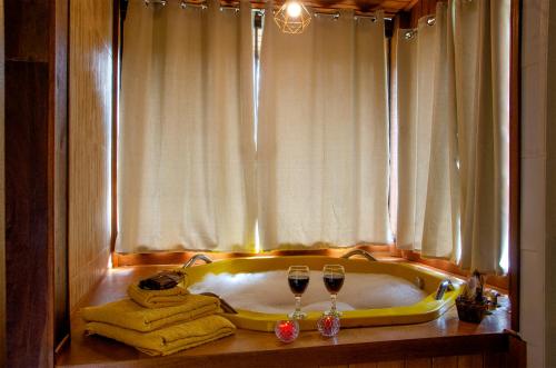 a bath tub with two glasses of wine and towels at Recanto Meu Pedacinho de Chão in Visconde De Maua