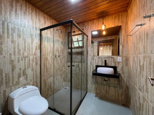 a bathroom with a toilet and a glass shower at Recanto Meu Pedacinho de Chão in Visconde De Maua