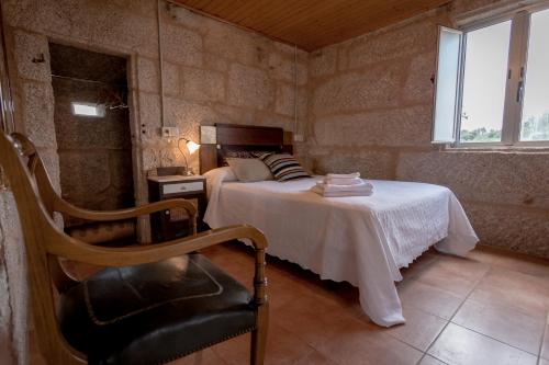 Un dormitorio con una cama y una silla y una ventana. en Casa dos Muiños, en Pontevedra