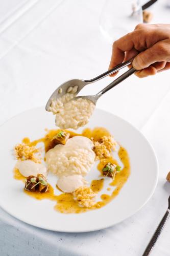 a person eating rice on a plate with a spoon at THE ONE CAORLE - Hotel & Apartments in Caorle