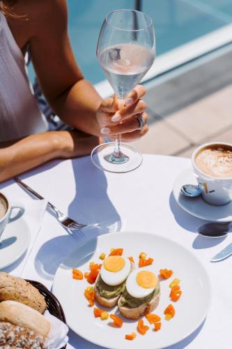 a person holding a glass of wine and a plate of food at THE ONE CAORLE - Hotel & Apartments in Caorle