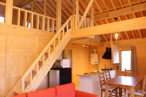 a staircase in a cabin with a table and a kitchen at ふらの田園コテージヌプリ in Nakafurano