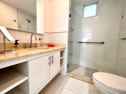 La salle de bains blanche est pourvue d'une douche et de toilettes. dans l'établissement Hermoso apartamento familiar /acceso directo a la playa. Morros 3, à Carthagène des Indes