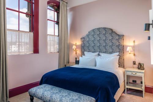 a bedroom with a blue and white bed and a chair at The Observatory Hotel Christchurch in Christchurch