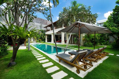 a couple of chairs and an umbrella next to a pool at Villa Zanissa in Seminyak