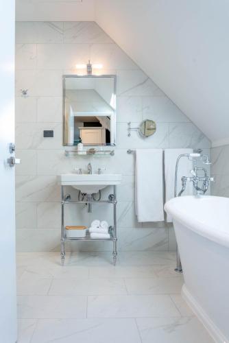 a white bathroom with a sink and a mirror at The Observatory Hotel Christchurch in Christchurch