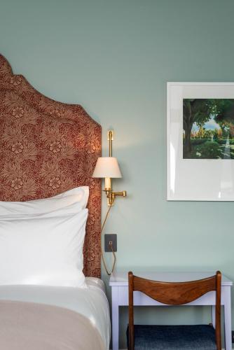 a bedroom with a bed and a lamp and a chair at The Observatory Hotel Christchurch in Christchurch
