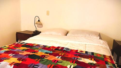 a bedroom with a bed with a colorful quilt on it at Los Apus Ollantaytambo in Cusco