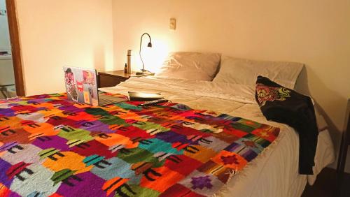 a bed with a colorful quilt on top of it at Los Apus Ollantaytambo in Cusco