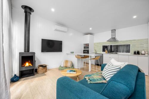 a living room with a blue couch and a fireplace at The Love Shack - romantic bungalow in Blairgowrie