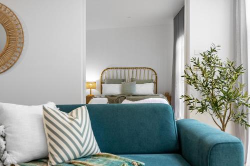 a living room with a blue couch and a bed at The Love Shack - romantic bungalow in Blairgowrie