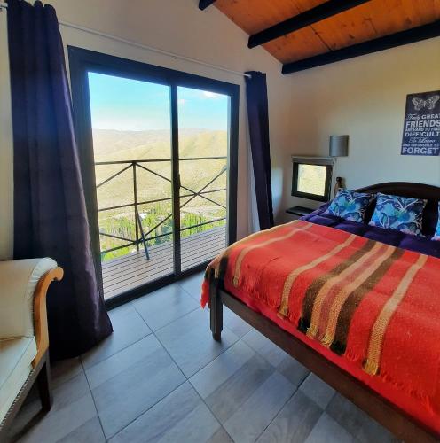 a bedroom with a bed and a large window at ArribadelValle - Casas de Altura in Potrerillos