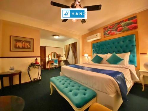a bedroom with a large bed with a blue headboard at HANZ Vuon Saigon Hotel & Spa in Ho Chi Minh City