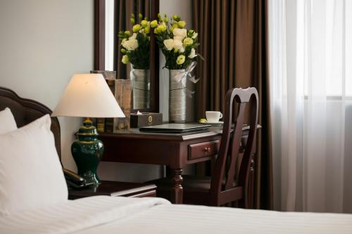 a bedroom with a desk with a lamp and flowers on it at Halais Hotel in Hanoi