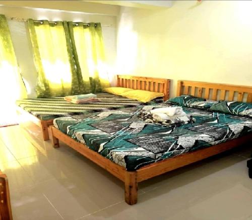 um quarto com 2 camas individuais e cortinas verdes em Condo Transient Near NAIA Airport T1234 with Unlimited WIFI v1 em Manila