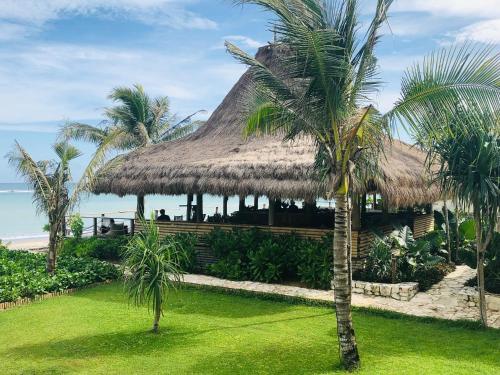 a resort with a thatched roof and palm trees at Sumba Beach House in Waikabubak