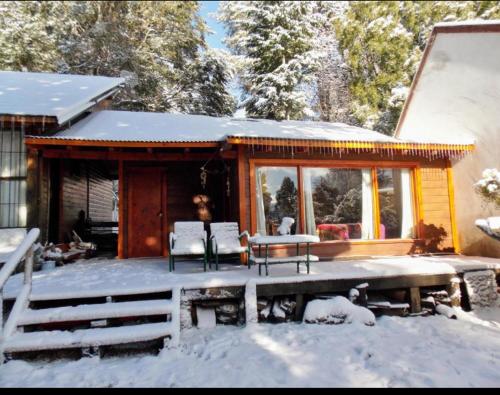 uma cabana de madeira com um deque na neve em Cabaña en el bosque em San Carlos de Bariloche