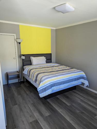 a bedroom with a bed and a yellow wall at Belle Aire Motel in Globe