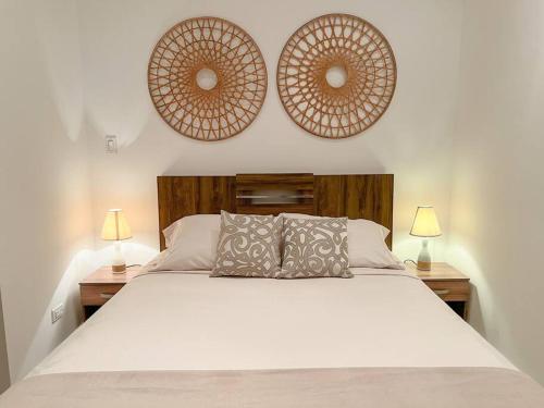 a bedroom with a bed with two lamps and two mirrors at Apartamento en el Corazón de Casco Viejo Panamá 12 in Panama City