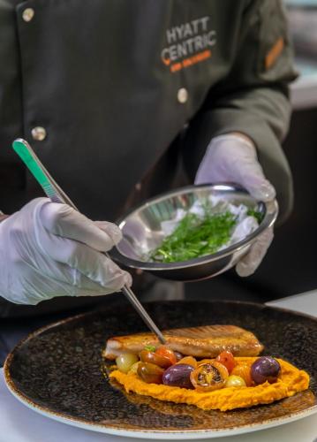 a person holding a plate of food with a bowl of food at Hyatt Centric San Salvador in San Salvador
