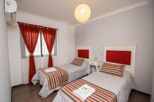 2 camas en una habitación con cortinas rojas en A & P, en Santa Fe