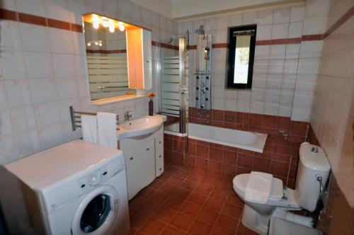 a bathroom with a toilet and a sink and a washing machine at Xenos Villa 2 With 5 Bedrooms private swimming pool, near the sea in Tigaki