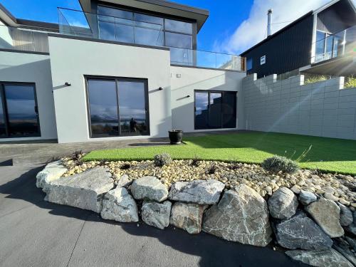 a house with a stone retaining wall and a yard at Starry Vista-Alpha in Lake Tekapo