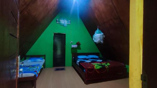a green room with two twin beds in it at Green Forest Tangkahan in Tangkahan