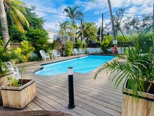 een zwembad op een houten terras met stoelen en planten bij LES CERISIERS BEACH RESIDENCE-Luxury 3Bd, Pool, Big Terrasse, 50mts from beach in Flic-en-Flac