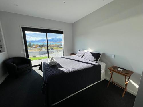 um quarto com uma cama e uma grande janela em Starry Vista-Beta em Lake Tekapo