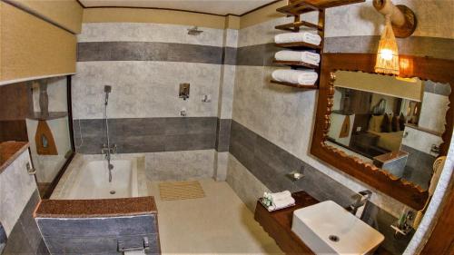 a bathroom with a tub and a sink and a mirror at Hotel Jungle Crown in Sauraha