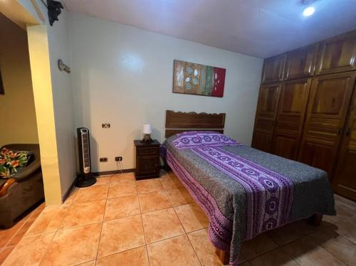 a bedroom with a bed with a purple blanket at Apartamento Sol Azul a 3 min del Aeropuerto SJO in Alajuela City
