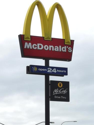 a sign for a mcdonalds restaurant with a street sign at Bay of Palms in Gold Coast