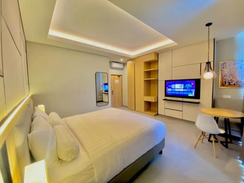 um quarto com uma cama, uma televisão e uma mesa em Front One King Hotel Tuban em Tuban